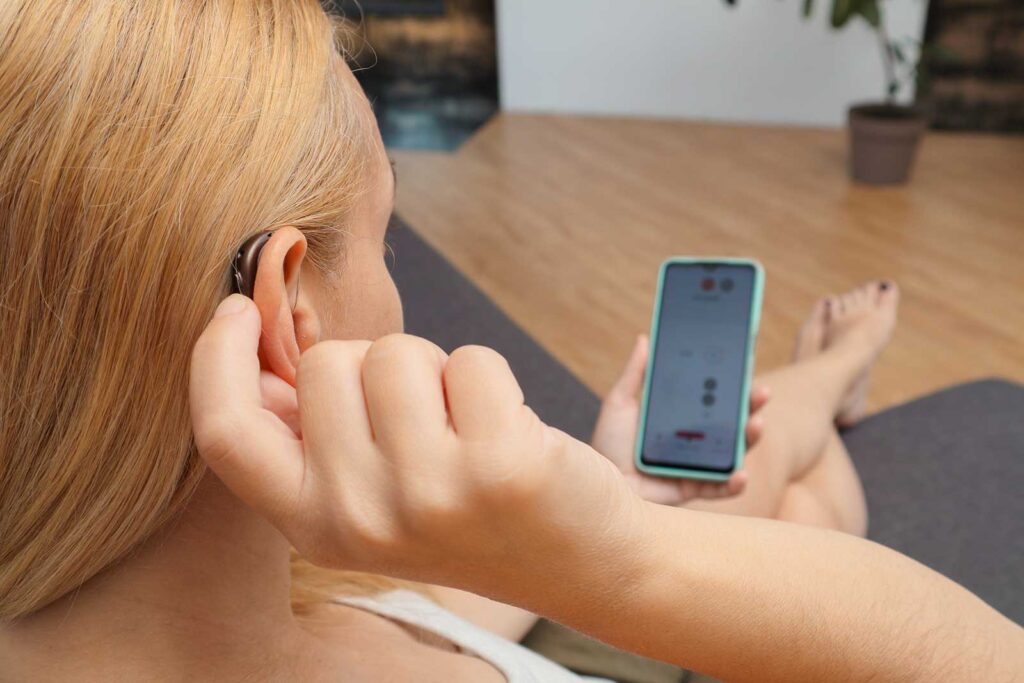 hearing-impaired-woman-working-with-smartphone-close-up-blonde-woman-wearing-hearing-aid-ear-pressing-button-while-using-smartphone-home